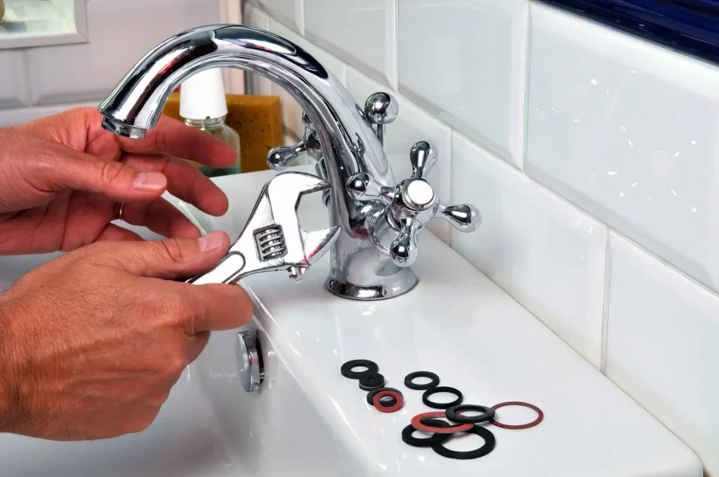 Plumber performing maintenance on a bathroom faucet in Greenfield