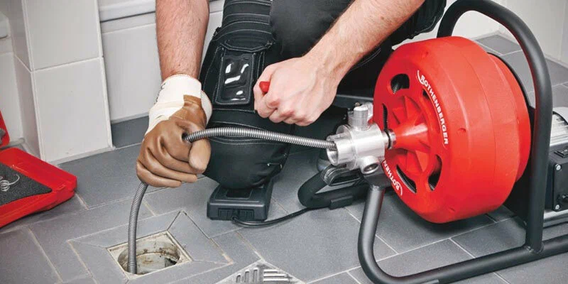Plumber using a drain-cleaning machine in Greenfield